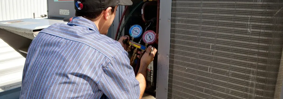 HVAC technician servicing a condenser unit in Vernon